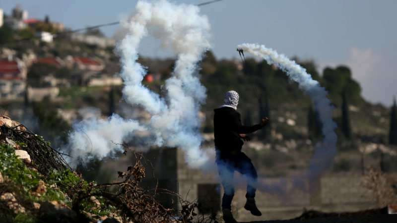 A Palestinian protester uses a slingshot to throw back a tear gas canister fired by Israeli soldiers during clashes after a protest against the expansion of Jewish settlements in Kufr Qadoom village near the West Bank city of Nablus, on Dec. 18, 2020. (Photo/RSS)