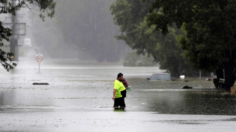 A man walks across a flooded street in Windsor, northwest of Sydney, New South Wales, Australia, Tuesday, March 23, 2021. Hundreds of people have been rescued from floodwaters that have isolated dozens of towns in Australia's most populous state New South Wales and forced thousands to evacuate their homes as record rain continues to inundate the country's east coast. (AP Photo/Rick Rycroft)