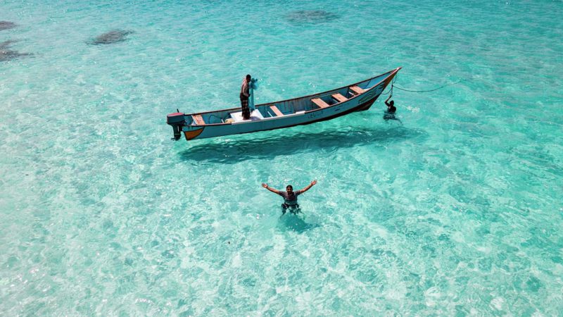 This picture taken on February 11, 2021 shows an aerial view of fishermen in the water by a boat off Shoab beach in the Yemeni Island of Socotra, a site of global importance for biodiversity conservation, located in the northwestern Indian Ocean some 200 kilometres south of the Yemeni mainland. - With its lush landscape, distinctive trees, unique animals and turquoise waters home to dolphins, Yemen is hoping its Socotra archipelago will become a dream destination despite the country's nightmarish conflict. The four islands and two rocky islets home to some 50,000 people have remained relatively untouched by the war that has devastated the mainland, with adventurous travelers showing a growing interest in visiting. (Photo by - / AFP)