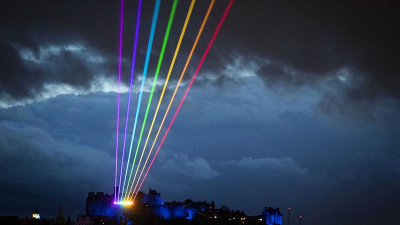 A rainbow light laser art installation by Yvette Mattern, illuminates the skyline in  Edinburgh, Scotland, during Edinburgh's flagship Burns festival entitled Burns and Beyond, Wednesday March 24, 2021.  The Scottish premiere of Global Rainbow starts Wednesday with the laser art installation by Yvette Mattern. (Jane Barlow/PA via AP)