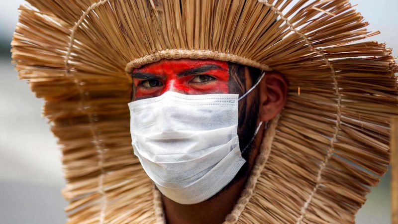 An indigenous man wears a protective mask during a protest against President Jair Bolsonaro's mining politics regarding indigenous lands, and demanding Brazilian Environment Minister Ricardo Salles' resignation, outside the Ministry of the Environment building in Brasilia on April 20, 2021, amid the COVID-19 pandemic. (Photo by Sergio Lima / AFP)