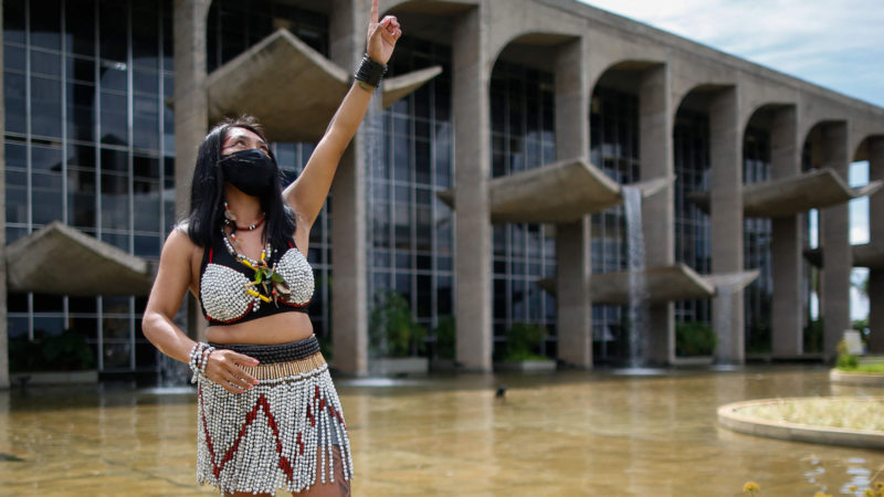 An indigenous woman wearing a protective mask gestures during a protest against Brazilian President Jair Bolsonaro's mining politics regarding indigenous lands, and demanding the resignation of Brazilian Environment Minister Ricardo Salles' resignation, outside the Ministry of the Environment building in Brasilia on April 20, 2021, amid the COVID-19 pandemic. (Photo by Sergio Lima / AFP)