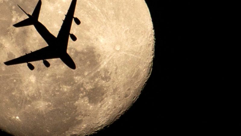 An aeroplane is pictured against an almost full moon, in Iraq's southern city of Basra, on April 25, 2021. (Photo by Hussein FALEH / AFP)