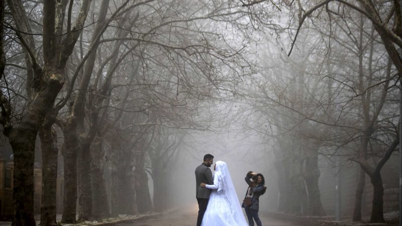 A bride and her groom pose for a photograph during a wedding photoshoot as heavy fog envelope the Sawfar village, Mount Lebanon Governorate of Lebanon, Saturday, April 3, 2021. Lebanese authorities imposed a three-day nationwide curfew as of Saturday morning to try limit the spread of COVID-19 during the Easter holidays. (AP Photo/Hassan Ammar)