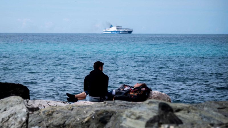 A couple takes a rest on the seaside rocks in the Old Seaside Village of Boccadasse on May 15, 2021 in Genoa. (Photo by Marco BERTORELLO / AFP)