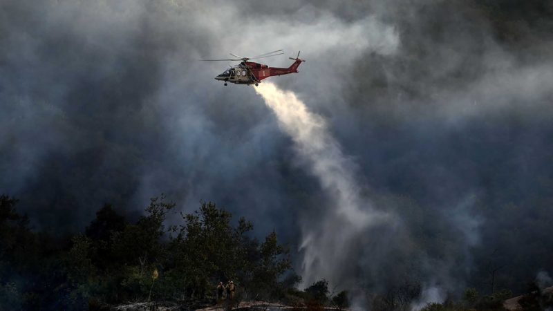 A firefighting helicopter drops water onto a brush fire scorching at least 100 acres in the Pacific Palisades area of Los Angeles on Saturday, May 15, 2021. (AP Photo/Ringo H.W. Chiu)