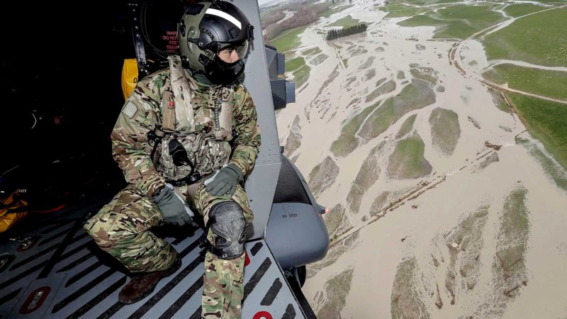 A soldier looks out from a helicopter on June 1, 2021 as they fly over the flood damage after heavy rains washed away bridges and cut roads in the Canterbury region. (Photo by CHRIS SKELTON / POOL / AFP)