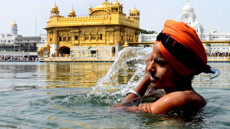 A Sikh devotee takes a bath in the holy sarovar (water tank) on the occasion of the 415th Sikh Guru Arjan Dev's martyrdom day at the Golden Temple in Amritsar on June 14, 2021. (Photo by NARINDER NANU / AFP)