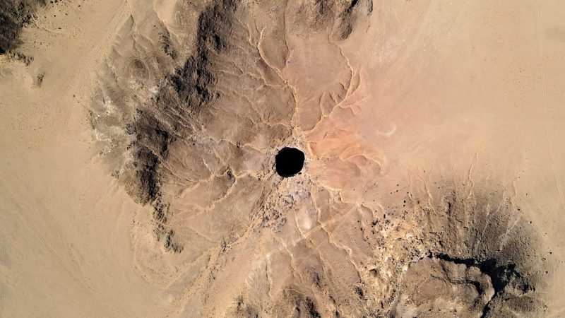 An aerial view taken on June 6, 2021 shows the Well of Barhout known as the "Well of Hell" in the desert of Yemen's Al-Mahra province. - Closer to the border with Oman than to the capital Sanaa 1,300 kilometres (800 miles) away, the giant hole in the desert of Al-Mahra province is 30 metres wide and thought to be anywhere between 100 and 250 metres deep. Local folklore says it was created as a prison for the demons -- a reputation bolstered by the foul odours rising from its depths. (Photo by - / AFP)