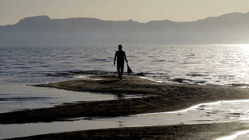 A man walks along a sand bar at the receding edge of the Great Salt Lake on June 13, 2021, near Salt Lake City. The lake has been shrinking for years, and a drought gripping the American West could make this year the worst yet. The receding water is already affecting nesting pelicans that are among millions of birds dependent on the largest natural lake west of the Mississippi River. (AP Photo/Rick Bowmer)