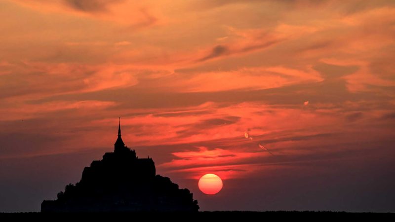 A picture shows the sunset over the Mont-Saint-Michel, in Normandy, northwestern France, on July 22, 2021. (Photo by Sameer Al-DOUMY / AFP)