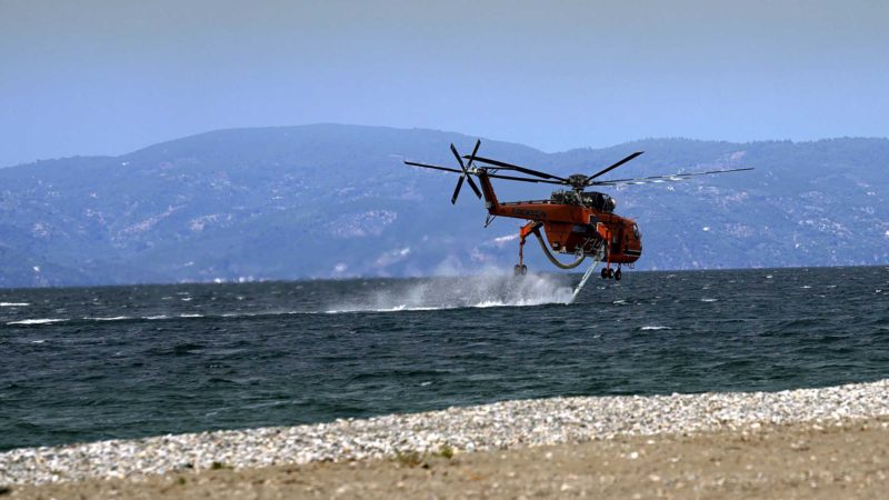 An helicopter fills water during a wildfire at Pefki village on Evia island, about 189 kilometers (118 miles) north of Athens, Greece, Monday, Aug. 9, 2021.Firefighters and residents battled a massive forest fire on Greece's second largest island for a seventh day Monday, fighting to save what they can from flames that have decimated vast tracts of pristine forest, destroyed homes and businesses and sent thousands fleeing. (AP Photo/Petros Karadjias)