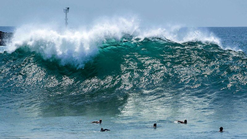 Body surfers watch from a distance as a large wave crashes onshore at the Wedge in Newport Beach, Calif. on Thursday, Aug. 19, 2021, as a big swell from the southern hemisphere moves on to Orange County beaches. (Mark Rightmire/The Orange County Register via AP)