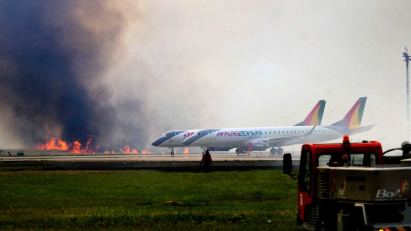 Firefighters try to extinguish a fire in the grasslands surrounding the Viru Viru airport in Santa Cruz, Bolivia on August 1, 2021. - Both national and international flights were cancelled after the fire got out of control due to strong winds. (Photo by RODRIGO URZAGASTI / AFP)