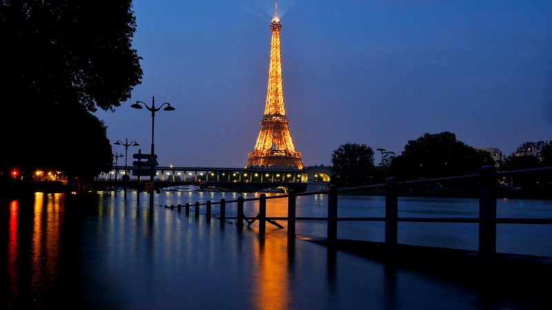 (FILES) In this file photo taken on June 05, 2016 at night shows the lighted Eiffel Tower in front of the Seine river in front Beaugrenelle in Paris. - Rising global temperature, rising sea levels, intensification of extreme events... The publication of the report of the Intergovernmental Panel on Climate Change (IPCC) is scheduled on August 9. (Photo by Bertrand GUAY / AFP)