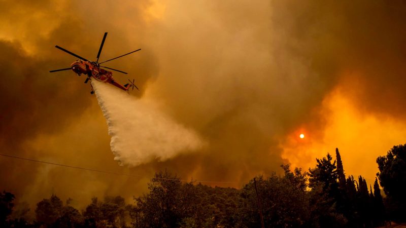 TOPSHOT - A Sikorsky S-64 Skycrane helicopter drops water over a forest to extinguish a fire in the village of Villa,  northwestern Athens, on August 18, 2021. - As devastating wildfires ravage Greece, experts say the blazes cast a harsh light on the failure to prepare against and contain them, threatening irreversible damage to the country's rich biodiversity. (Photo by ANGELOS TZORTZINIS / AFP)