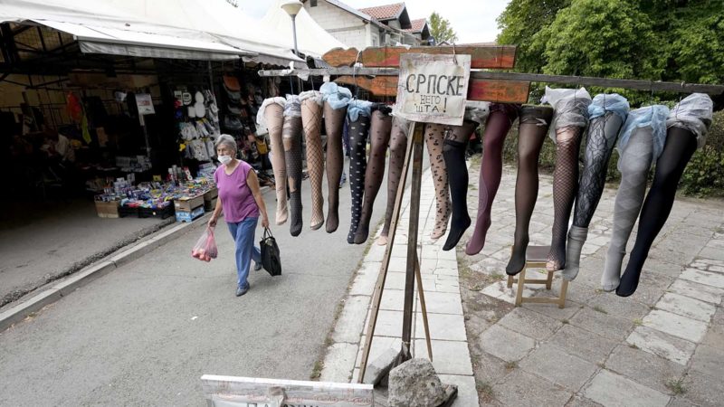 A woman wearing a mask to protect against the spread of the coronavirus, walks by hosiery by a stall at the flea market in Belgrade, Serbia, Tuesday, Aug. 24, 2021. (AP Photo/Darko Vojinovic)