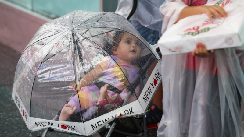 (210822) -- NEW YORK, Aug. 22, 2021 (Xinhua) -- A child is seen in a stroller covered with an umbrella in the rain caused by tropical storm Henri, in Times Square in New York, the United States, on Aug. 22, 2021. The hurricane warning for Long Island, the southern coast of New England and Block Island in the northeast of the United States has been changed to a tropical storm warning, said an updated advisory from the National Hurricane Center (NHC) on Sunday morning. (Xinhua/Wang Ying)