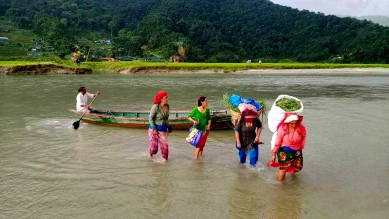 पोखरा– १८ स्थित फेवातालको शिरान हर्पन खोलामा मेलापात सकेर घाँसको भारी लिएर डुङ्गाबाट घर फर्कंदै स्थानीय महिला । सो स्थानको पुल केही समय पहिला बाढीले बगाएपछि स्थानीय बासिन्दा डुङ्गाको सहारामा आउ जाउ गर्न थालेका छन । तस्वीर : जमुनावर्षा शर्मा/रासस