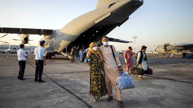 People evacuated from Afghanistan pose in front of a German Bundeswehr airplane after arriving at the airport in Tashkent, Uzbekistan, Tuesday, Aug. 17, 2021. The federal armed forces evacuates German citizens and local Afghan forces from Kabul. (AP Photo/Bundeswehr via AP)