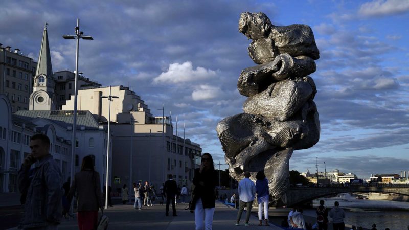 People walk next to "Big Clay #4" artwork by the Swiss artist Urs Fischer on Bolotnaya embankment in Moscow, Russia, Monday, Aug. 23, 2021. A 12-meter aluminum sculpture copies forms of an ordinary hunk of clay and reveals the artist's magnified palm creases and fingerprints. (AP Photo/Pavel Golovkin)