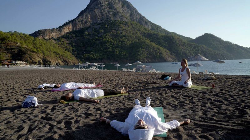 People practice yoga on the beach in Adrasan, west of Antalya, Turkey, Friday, Sept. 24, 2021. People enjoy the warm weather in the Mediterranean region as the first snow blanketed the high mountains in north eastern Turkey. (AP Photo/Burhan Ozbilici)