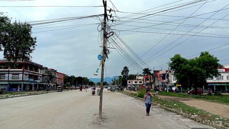 कैलालीको टीकापुर नगरपालिका– १ स्थित जमरा पुलदेखि बसपार्कसम्म निर्माण भइरहेको छ लेन सडकको बीच भागमा रहेको विद्युत् पोल ।  विद्युत् पोल नसारेरै सडकको बेसको काम सम्पन्न भई कालोपत्रेको काम सुरु भएको छ । तस्वीर : झलनाथ खनाल/रासस