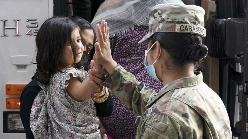 FILE - In this Monday, Aug. 30, 2021, file photo, Army Pfc. Kimberly Hernandez gives a high-five to a girl evacuated from Kabul, Afghanistan, before boarding a bus after they arrived at Washington Dulles International Airport, in Chantilly, Va. U.S. religious groups of many faiths are gearing up to assist the thousands of incoming refugees. Roughly 400 Afghan refugees will resettle in Idaho over the next fiscal year, officials with the International Rescue Committee in Boise said on Tuesday, Sept. 14, 2021. About 50,000 Afghans are expected to be admitted to the United States under a program called "Operation Allies Welcome." The group will include translators, drivers and others who helped the U.S. military during the 20-year war and who feared reprisals from the Taliban after they quickly seized power last month. (AP Photo/Jose Luis Magana, File)