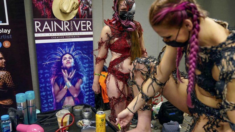 Paladins of Cosplay members Shanna, left, and Allison, neither of whom gave last names, put on and repair their costumes at the New York Comic Con in New York, Friday, Oct. 8, 2021. Although the convention was canceled last year because of COVID-19, this year attendees were welcomed back with mandatory masking and proof of vaccination. (AP Photo/Seth Wenig)