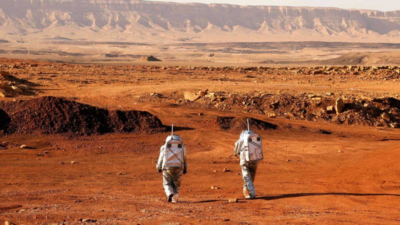 TOPSHOT - A couple of astronauts from a team from Europe and Israel walk in spacesuits during a training mission for planet Mars at a site that simulates an off-site station at the Ramon Crater in Mitzpe Ramon in Israel's southern Negev desert on October 10, 2021. - Six astronauts from Portugal, Spain, Germany, the Netherlands, Austria, and Israel will be cut off from the world for a month, from October 4-31, only able leave their habitat in spacesuits as if they were on Mars. Their mission, the AMADEE-20 Mars simulation, will be carried out in a Martian terrestrial analog and directed by a dedicated Mission Support Center in Austria, to conduct experiments ahead of future human and robotic Mars exploration missions. (Photo by JACK GUEZ / AFP)