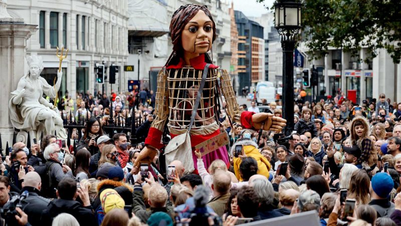 'Little Amal', a giant puppet depicting a Syrian refugee girl, makes her way to St Paul's Cathedral in the City of London on October 23, 2021, as part of the international art project The Walk. - 'Little Amal' was designed by The Handspring Puppet Company and represents a Syrian refugee child and the millions of displaced children worldwide. 'Little Amal' has made an 8000 km journey across Europe to the United Kingdom to raise awareness of the challenges faced by refugee children. (Photo by Tolga Akmen / AFP)