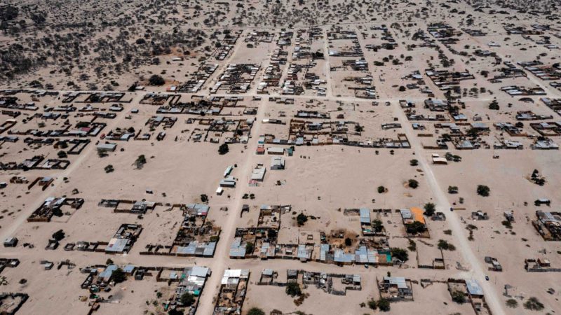 Aereal view of the "Refugio Santa Rosa", a camp of precarious straw houses and tents, installed in 2017 by the Civil Defence on the side of the Pan-American highway, 980 km in Piura north of Lima on October 17, 2021. - Thousands of climate migrants who lost their homes and livelihoods due to the El Nino Costero phenomenon five years ago, live in precarious camps in the desert in northern Peru. (Photo by ERNESTO BENAVIDES / AFP)