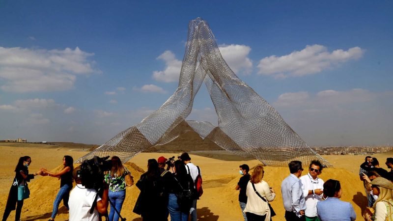 GIZA (EGYPT), Oct. 21, 2021 (Xinhua) -- Visitors gather in front of Italian artist Lorenzo Quinn's sculpture "Together" during an international art exhibition in Giza, Egypt, on Oct. 21, 2021. Egypt launched on Thursday the first international art exhibition at the Great Pyramids of Giza and their surrounding plateau with the participation of artists from Egypt and other countries. (Xinhua/Ahmed Gomaa)