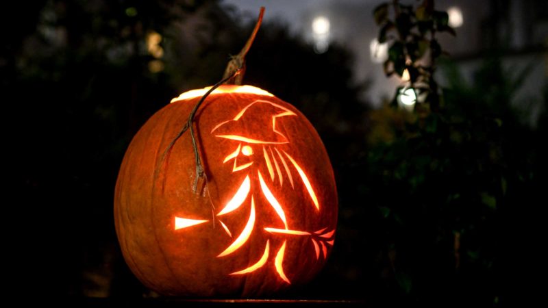 TOPSHOT - This photograph shows a jack-o'-lantern made with a carved pumpkin representing a witch and her broom, during Halloween night, in Lausanne, on October 31, 2021. (Photo by Fabrice COFFRINI / AFP)