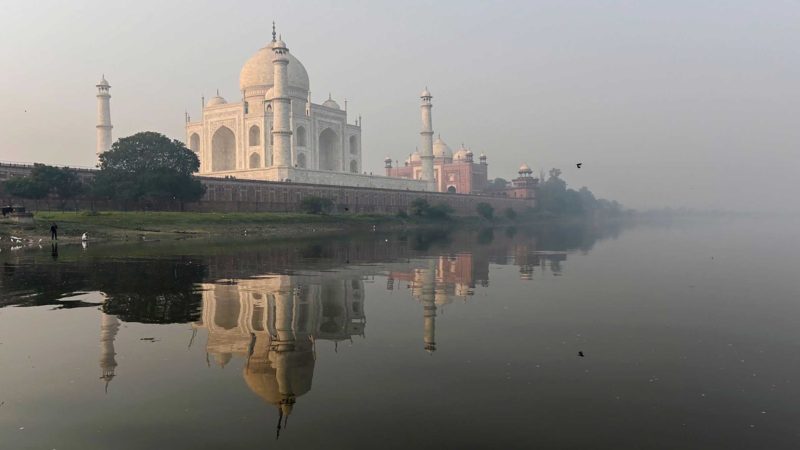 TOPSHOT - Men (L) pray at the banks of the Yamuna River near the Taj Mahal amid smoggy conditions in Agra on November 16, 2021. (Photo by Sajjad HUSSAIN / AFP)