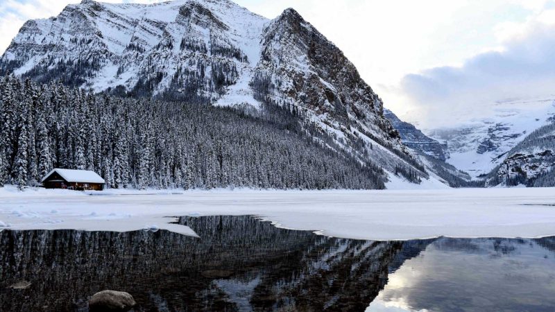 A snow covered mountain is reflected in Lake Louise ahead of a winter storm in Banff National Park, Alberta, Canada on November 29, 2021. (Photo by Patrick T. FALLON / AFP)