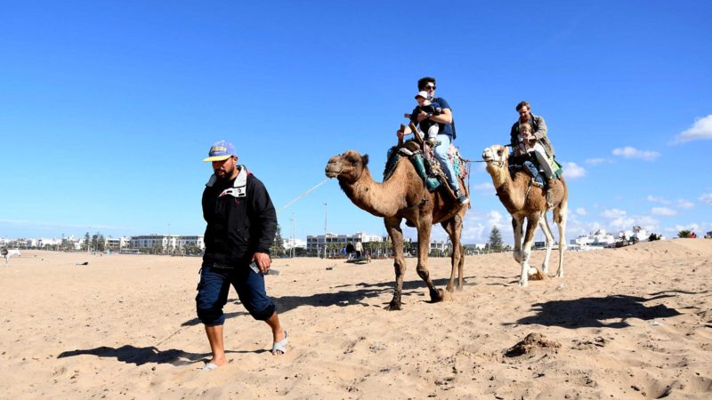 (211120) -- ESSAOUIRA (MOROCCO), Nov. 20, 2021 (Xinhua) -- Tourists ride camels on a beach in Essaouira, western Morocco, on Nov. 20, 2021. (Photo by Chadi/Xinhua)