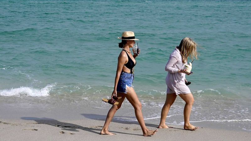 People walk along the beach, Monday, Nov. 15, 2021, in Miami Beach, Fla. Cooped-up tourists eager for a taste of Florida's sandy beaches, swaying palm trees and warmer climates are visiting the Sunshine State in droves, topping pre-pandemic levels in recent months. (AP Photo/Lynne Sladky)
