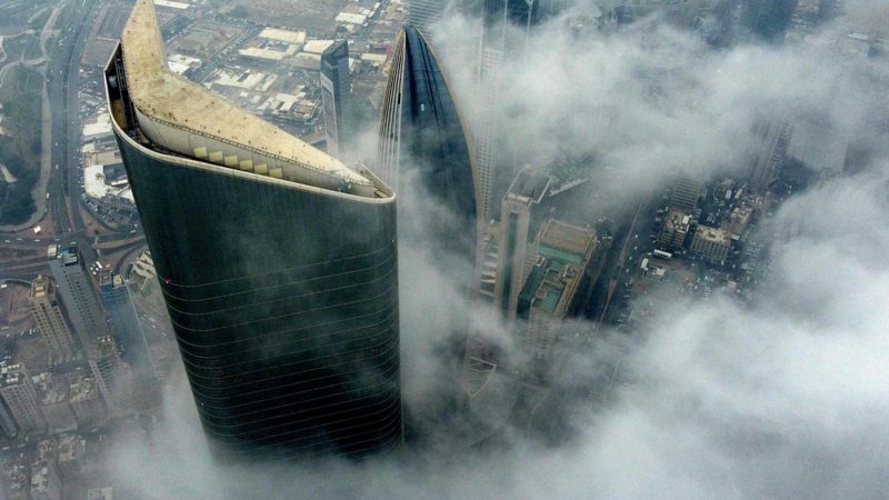 An aerial picture taken by drone shows Al-Hamra tower (L), the headquarters of  The National Bank of Kuwait (C) and Al-Rayah tower (R), caught in heavy fog in Kuwait City, on December 30, 2021. (Photo by YASSER AL-ZAYYAT / AFP)