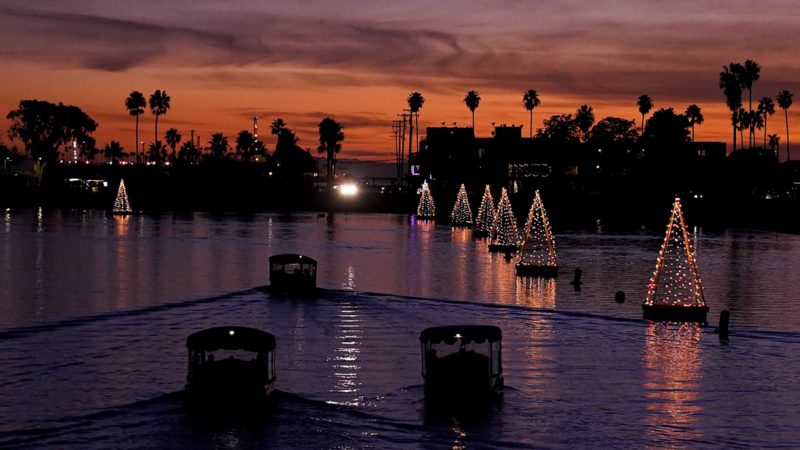 Boats make their way past floating Christmas tree lights on Sunday, Dec. 19, 2021, in Long Beach, Calif. (AP Photo/Ashley Landis)